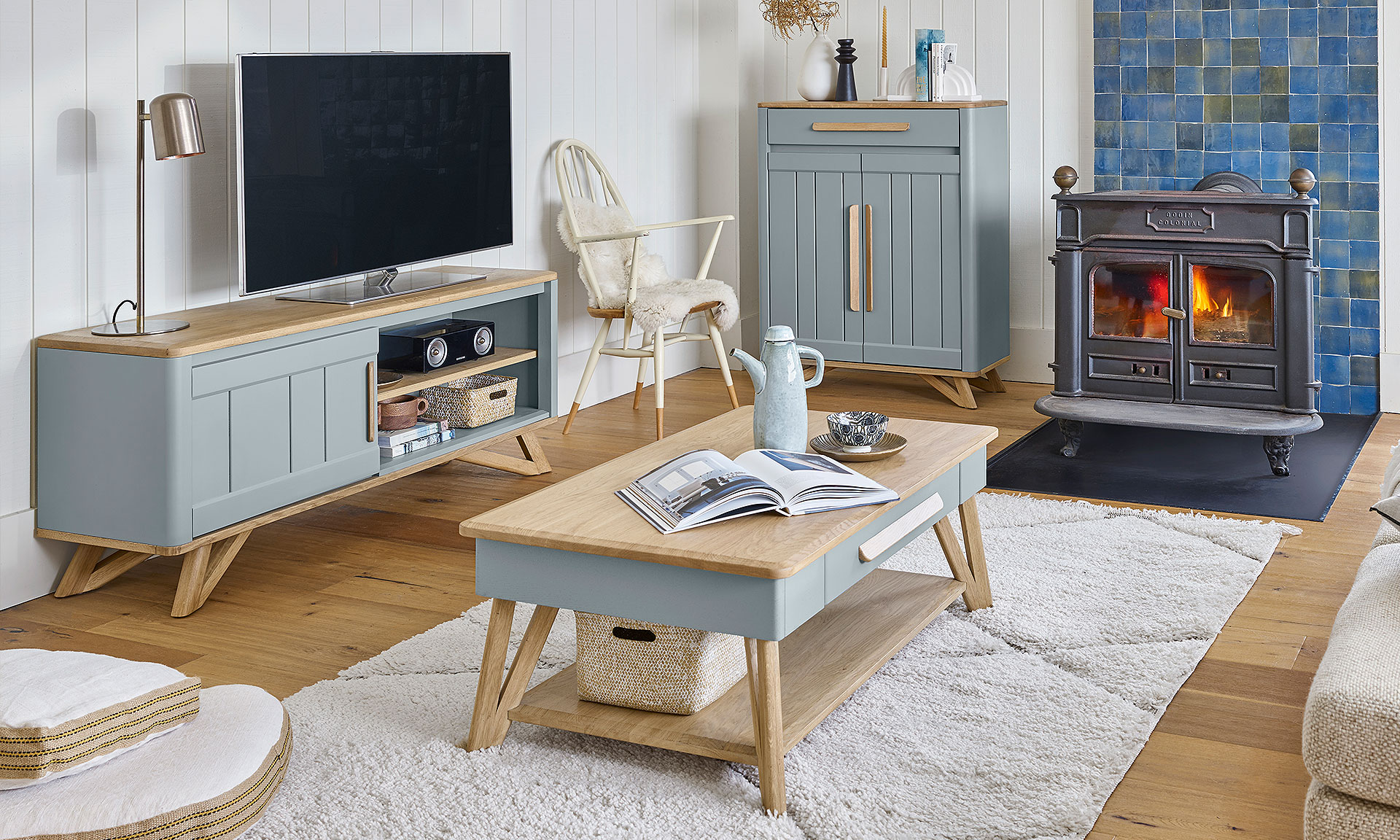 Photo présentant un salon avec une table basse/dinette, un meuble tv et un meuble d'entrée haut. Chaque meuble à une finition en chêne massif blond et une peinture couleur baltique.