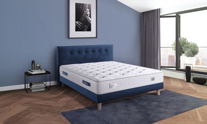 Un matelas avec Ressorts Ensachés avec un sommier et tête de lit en bleu velours.